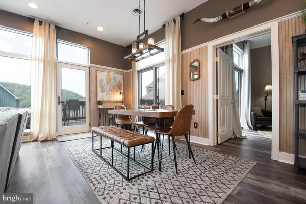 a dining room with wooden floor a chandelier a wooden table and chairs