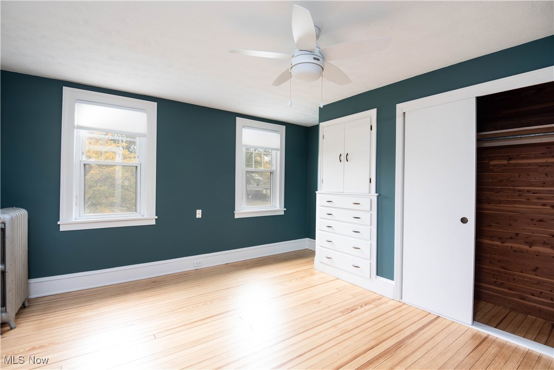 7003 Brecksville Road Independence, OH 44131 - Photo 22 of 35 Unfurnished bedroom featuring radiator heating unit, light wood-style floors, ceiling fan, and a closet