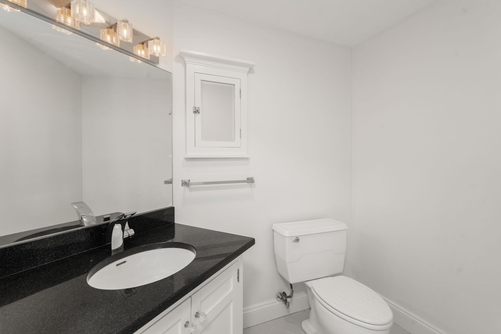 280 Boylston Street, Unit 905 Newton, MA 02467 - Photo 13 of 22 a bathroom with a granite countertop sink mirror vanity and toilet