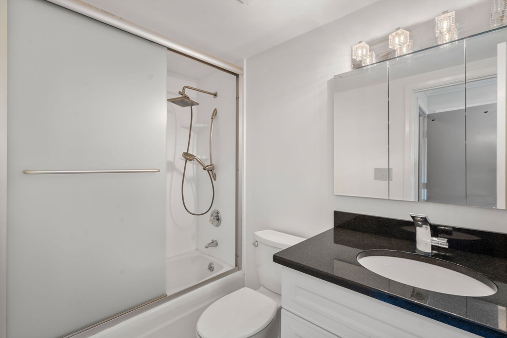280 Boylston Street, Unit 905 Newton, MA 02467 - Photo 17 of 22 a bathroom with a granite countertop sink toilet a mirror and shower