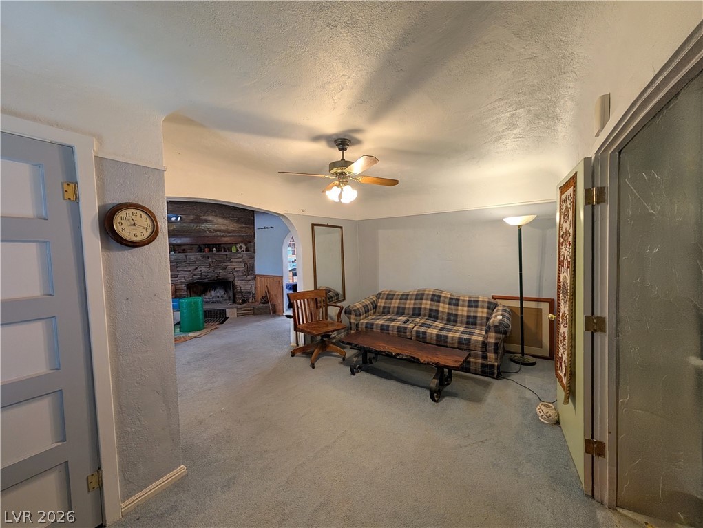 997 Phillips Street Panaca, NV 89042 - Photo 10 of 19 A cozy living space features soft carpeting and a rustic stone fireplace, creating an inviting atmosphere.