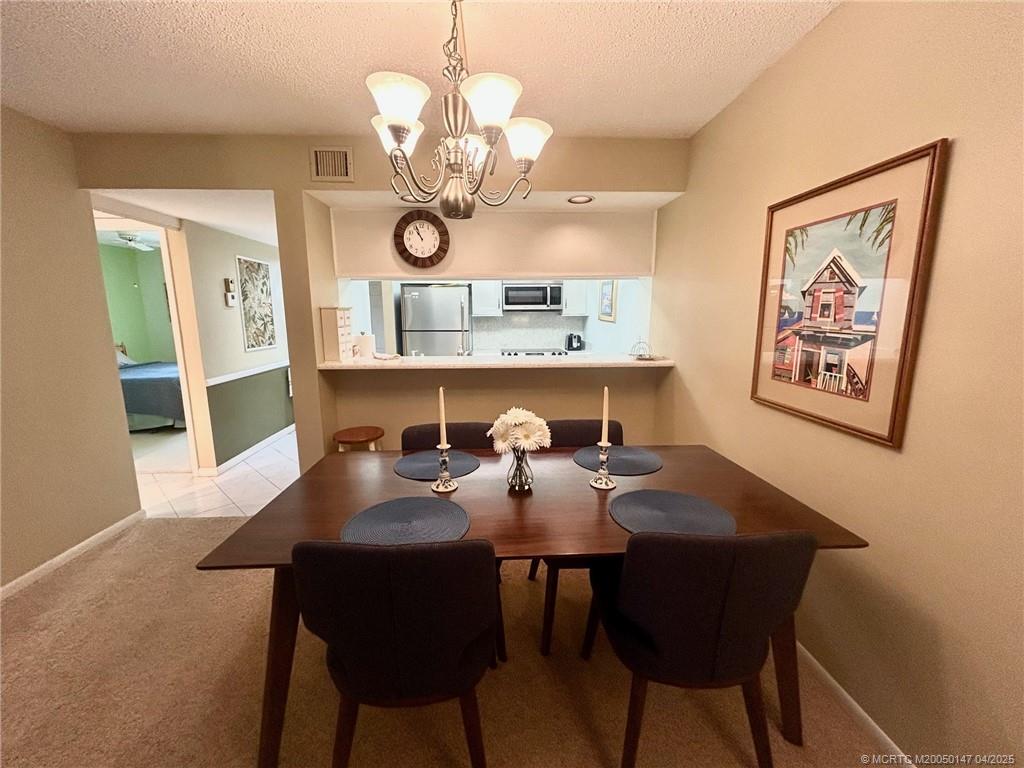 5811 Northeast Gulfstream Way, Unit 4002 Stuart, FL 34996 - Photo 21 of 39 a view of a dining room with furniture a chandelier and wooden floor