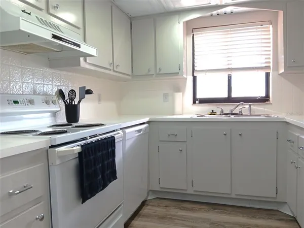 a kitchen with white cabinets appliances a sink and a window