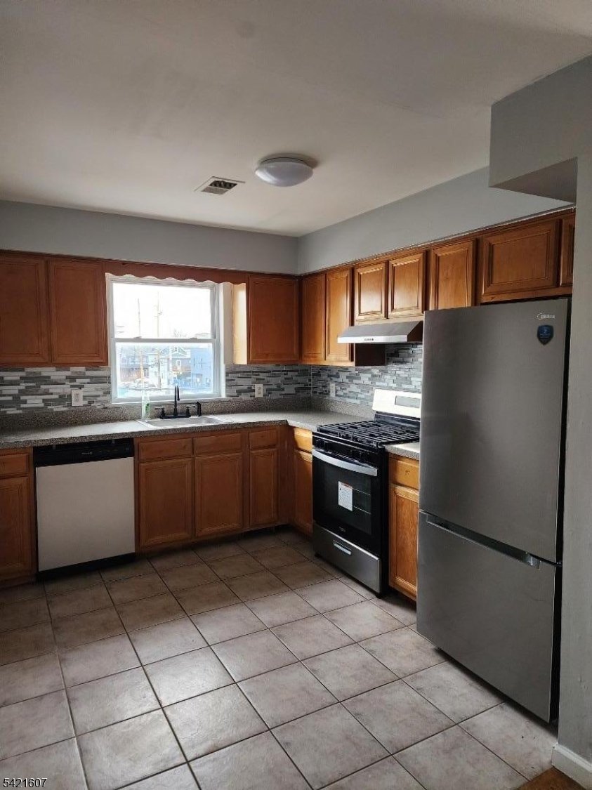 16 5th Street, Unit 2 Elizabeth Port, NJ 07206 - Photo 2 of 14 a kitchen with granite countertop stainless steel appliances a refrigerator sink and cabinets