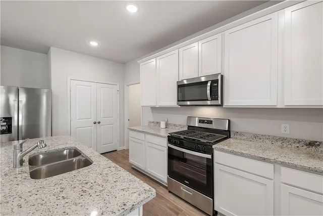 a kitchen with granite countertop white cabinets and stainless steel appliances