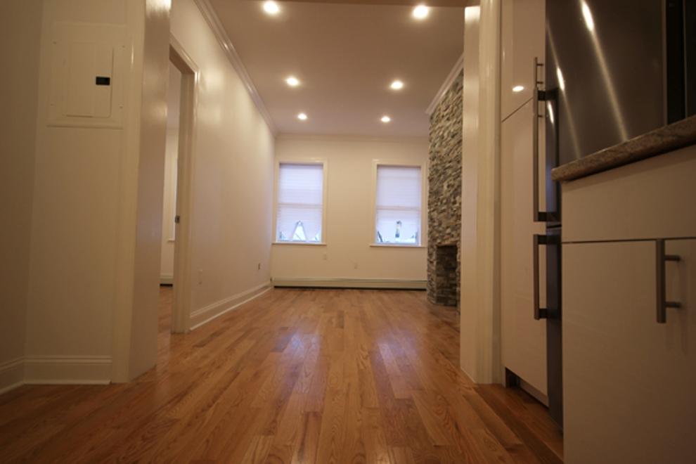 a view of a hallway with wooden floor and a bathroom