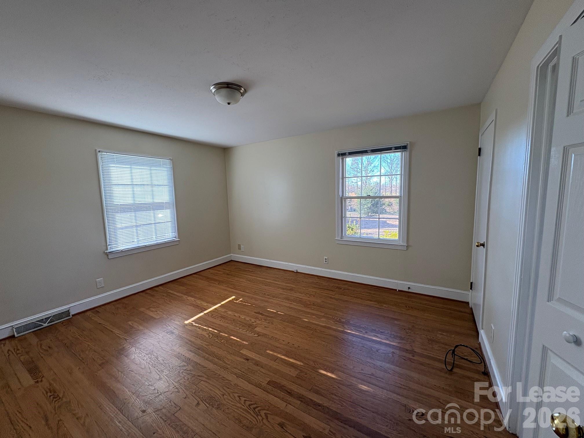 312 Stevens Street Monroe, NC 28112 - Photo 5 of 10 an empty room with wooden floor and windows