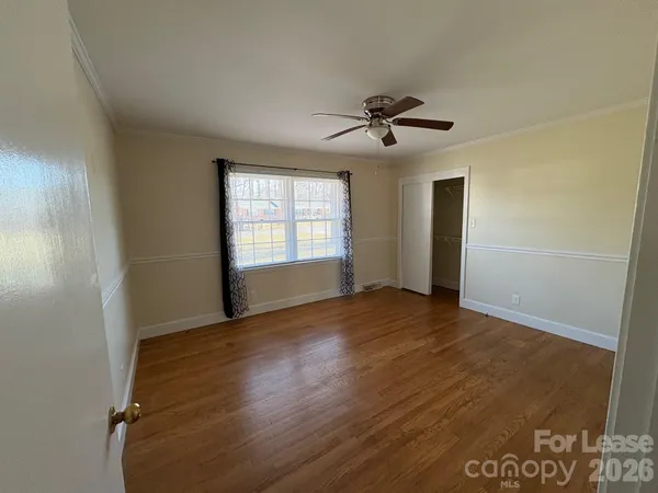 a view of empty room with wooden floor and fan