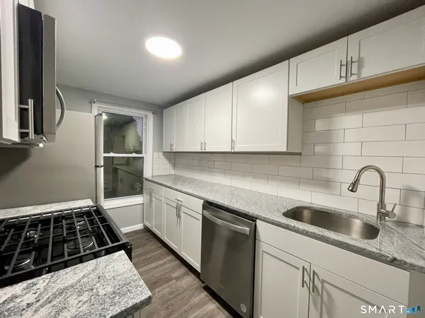 a kitchen with granite countertop a sink stove and cabinets