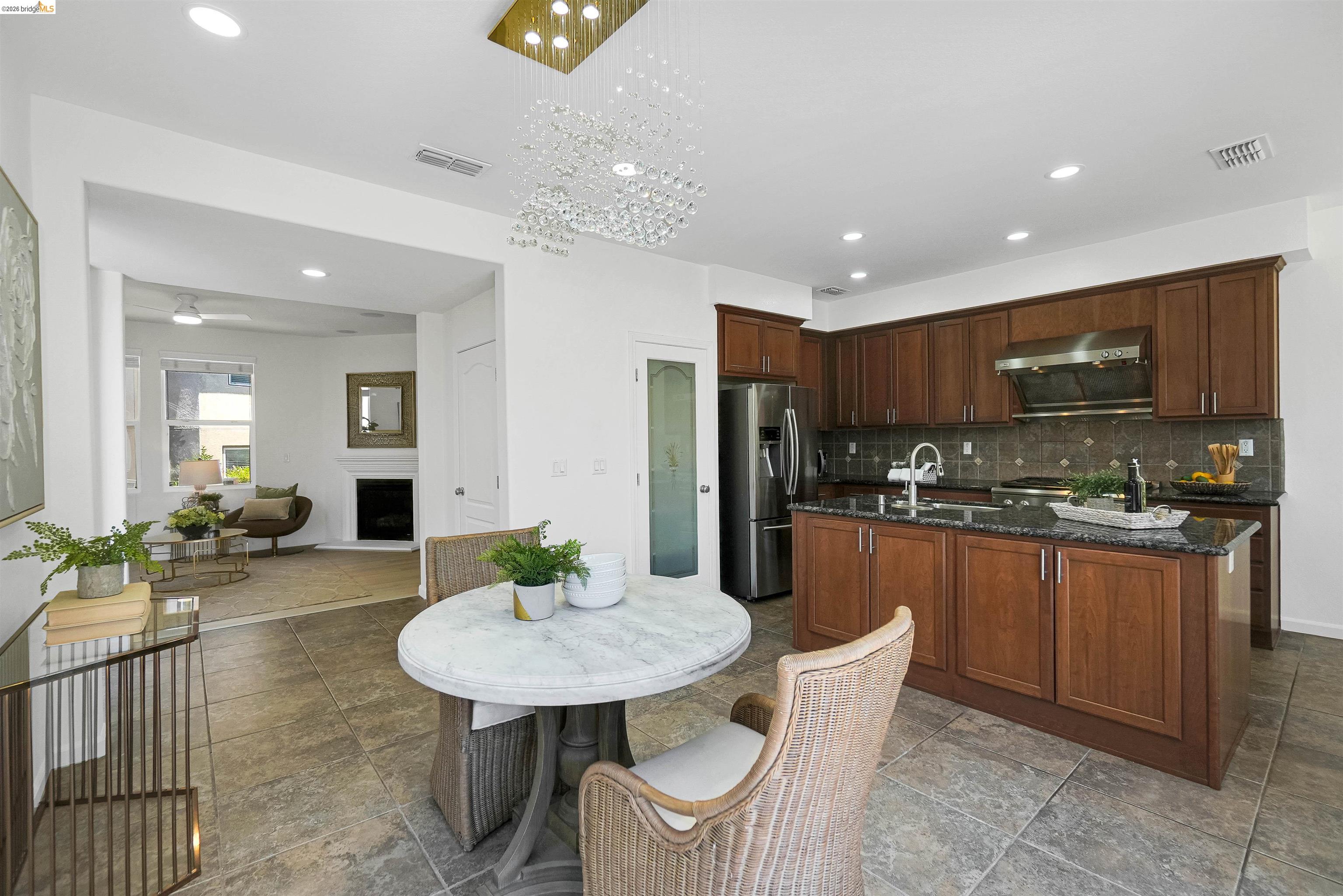 449 Constantine Court San Ramon, CA 94583 - Photo 19 of 63 Kitchen featuring a central island with an undermount sink, dark wood cabinetry, stainless steel appliances, and a tile backsplash