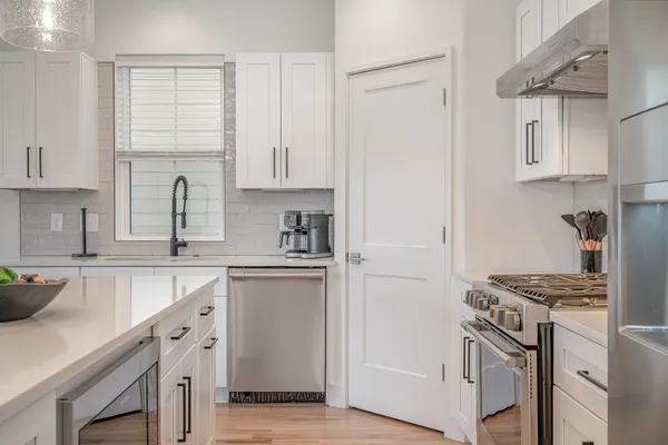 a kitchen with stainless steel appliances granite countertop a stove a refrigerator and a white cabinets