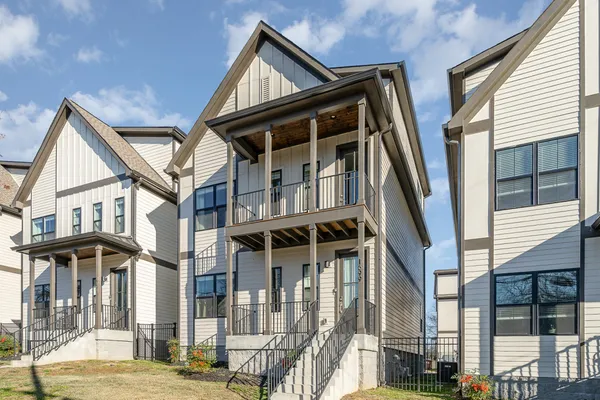 a view of small white house with large windows and a tree