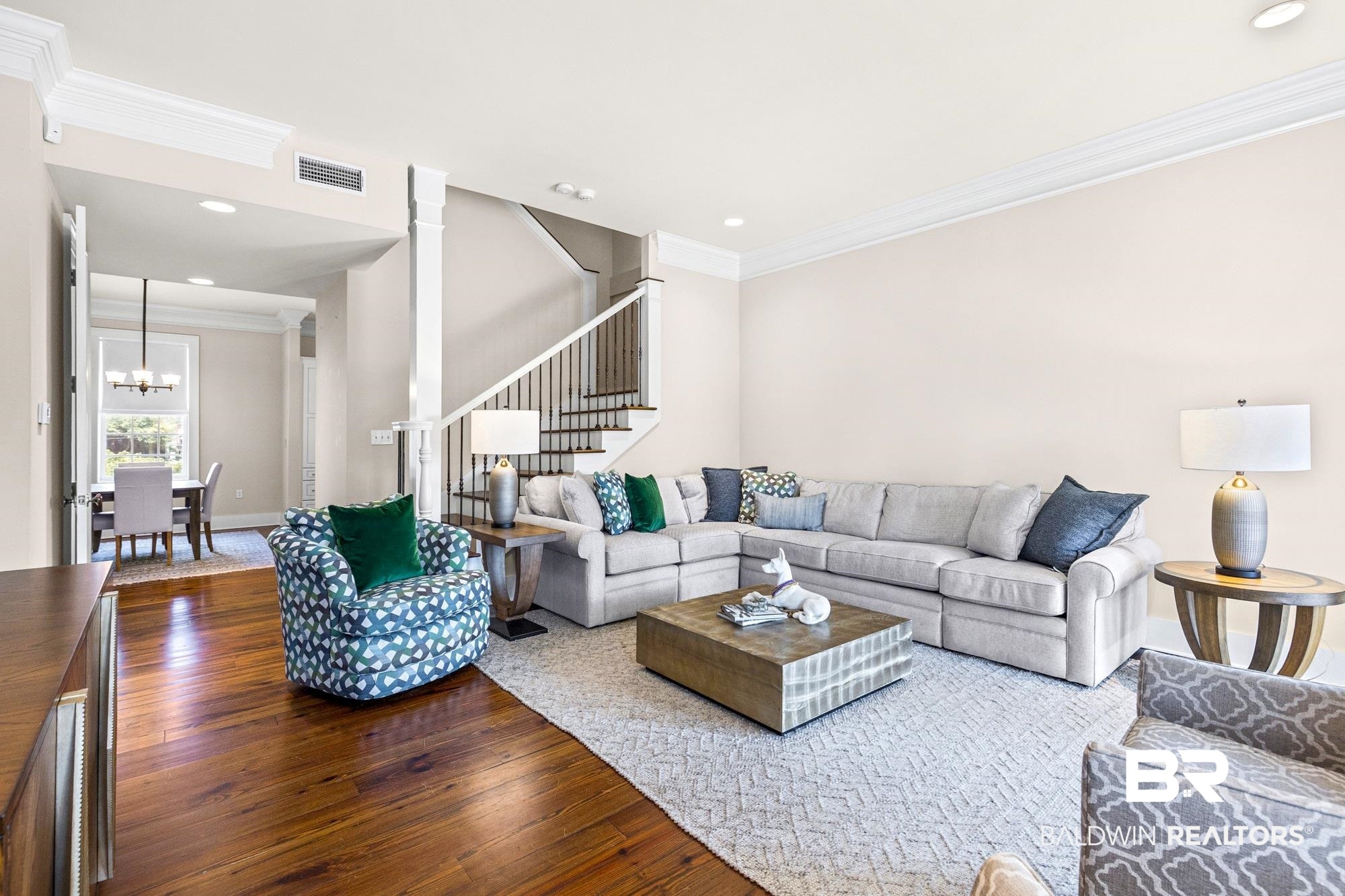 701 Dauphin Street, Unit A Mobile, AL 36602 - Photo 5 of 31 Spacious living area featuring rich wood-finish flooring, a grand staircase with dark iron balusters, high ceilings, recessed lighting, and elegant crown molding