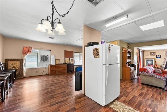 a kitchen with stainless steel appliances granite countertop a refrigerator a oven a dining table and chairs with wooden floor