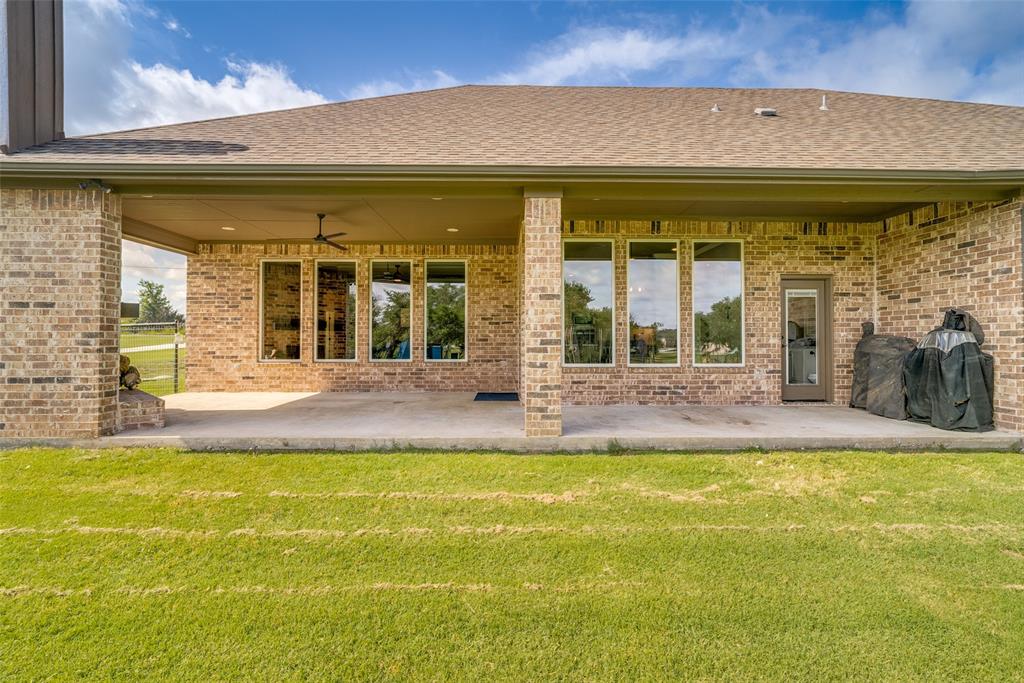 6913 Veal Station Road Weatherford, TX 76085 - Photo 26 of 31 Expansive concrete patio extending across the rear elevation, featuring a brick exterior and a covered porch area