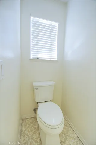 a white toilet sitting in a bathroom next to a window