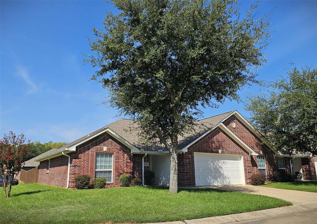 Expansive lawn bordered by a wood privacy fence, featuring a brick exterior and sliding glass door access