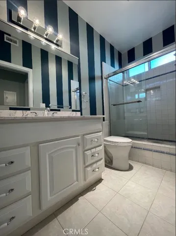 a bathroom with a granite countertop sink a toilet and a shower