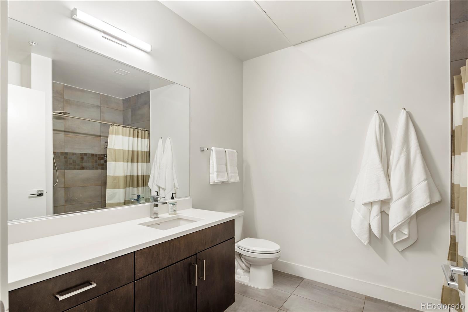 1898 South Bannock Street, Unit 103 Denver, CO 80223 - Photo 13 of 22 a bathroom with a sink a toilet and a mirror