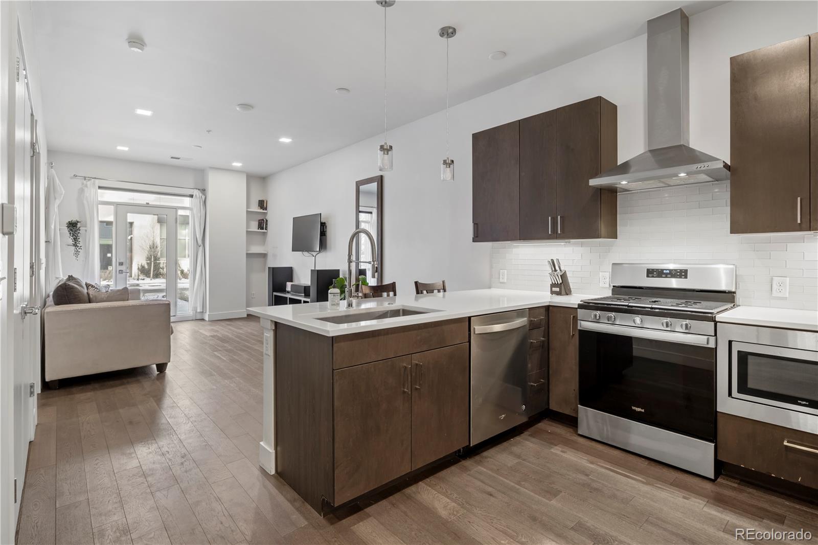 1898 South Bannock Street, Unit 103 Denver, CO 80223 - Photo 3 of 22 a large kitchen with stainless steel appliances granite countertop a sink and a stove