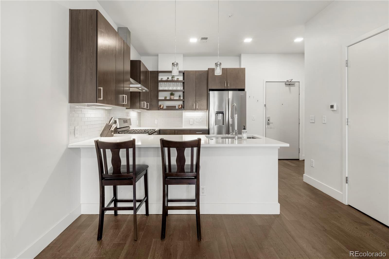 1898 South Bannock Street, Unit 103 Denver, CO 80223 - Photo 4 of 22 a kitchen with a table chairs refrigerator and microwave