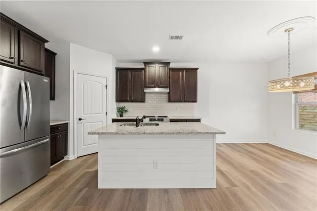 a kitchen with stainless steel appliances granite countertop a refrigerator a stove and a sink