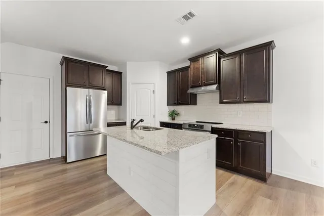 a kitchen with stainless steel appliances granite countertop a refrigerator stove top oven and sink