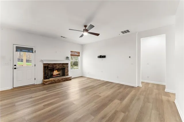 an empty room with wooden floor fireplace and windows