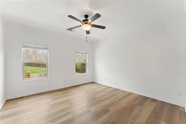a view of empty room with wooden floor and fan