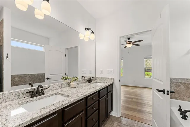 a bathroom with a granite countertop sink a large mirror and a bathtub