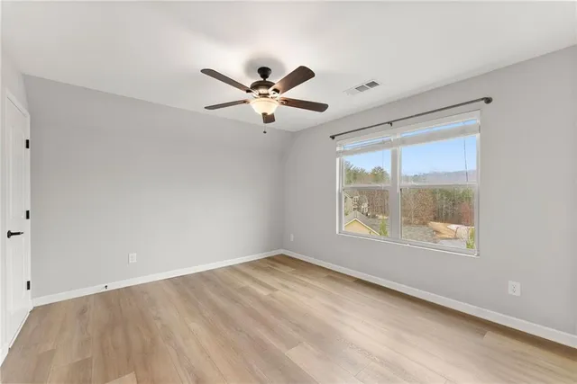 a view of an empty room with a window and a ceiling fan