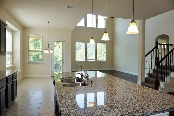 a kitchen with granite countertop a sink a stove and refrigerator