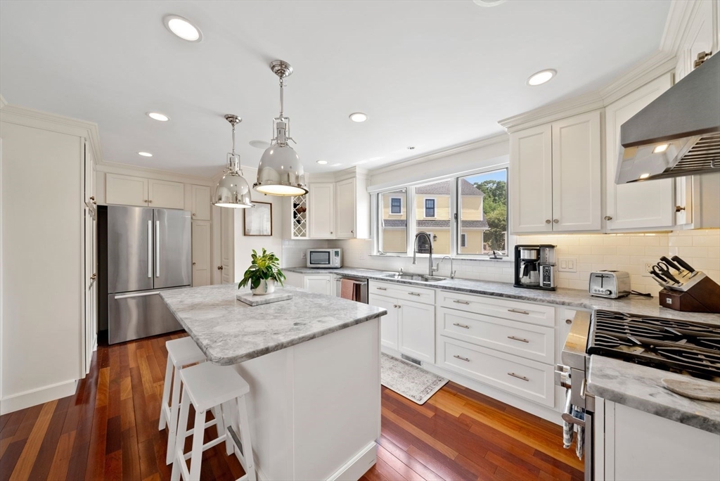 1111 Brook Road Milton, MA 02186 - Photo 5 of 22 a kitchen with stainless steel appliances kitchen island granite countertop a stove a sink dishwasher and white cabinets with wooden floor