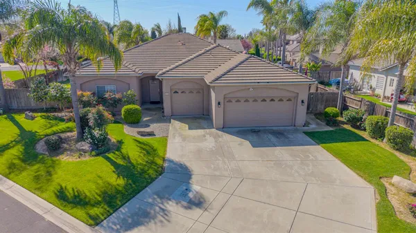 a view of a house with a yard and palm trees