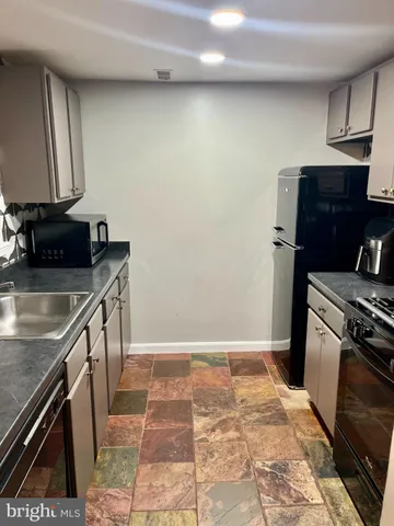 a kitchen with granite countertop a sink a stove top oven and refrigerator