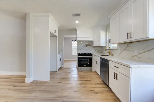a view of an empty room with wooden floor and a ceiling fan