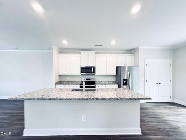 a large kitchen with granite countertop a stove top oven a sink a counter space and cabinets