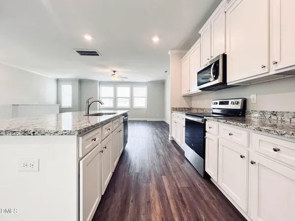 a large kitchen with stainless steel appliances granite countertop a lot of counter space and wooden floors