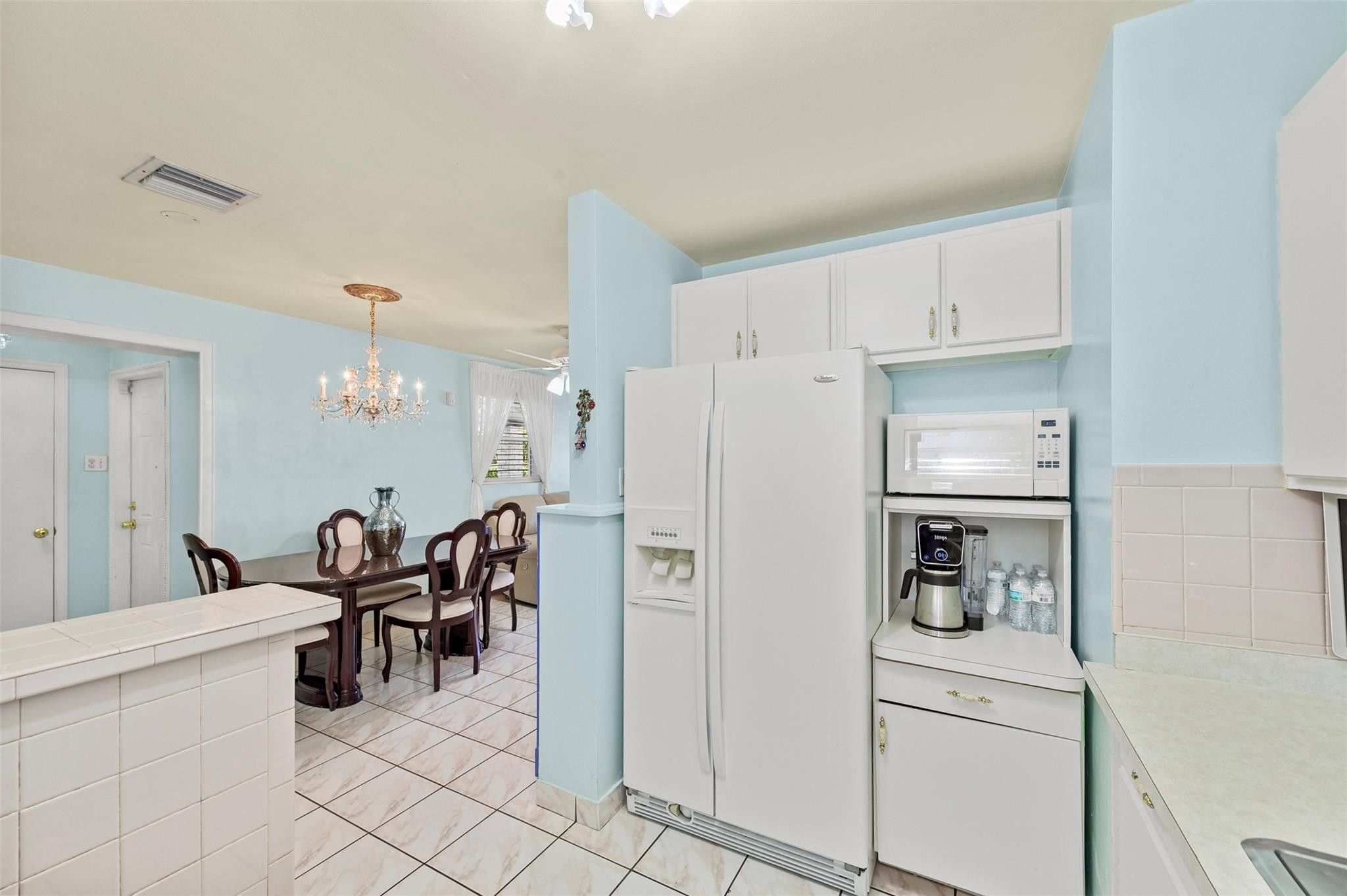946 Alamanda Road West Palm Beach, FL 33405 - Photo 8 of 56 a kitchen with a refrigerator a stove top oven a dining table and chairs