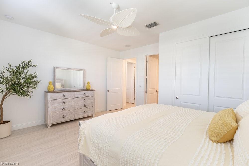 16364 Viansa Way, Unit 202 Naples, FL 34110 - Photo 19 of 39 a spacious bedroom with a bed and a potted plant