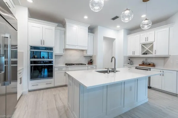 a kitchen with kitchen island granite countertop a sink cabinets and stainless steel appliances