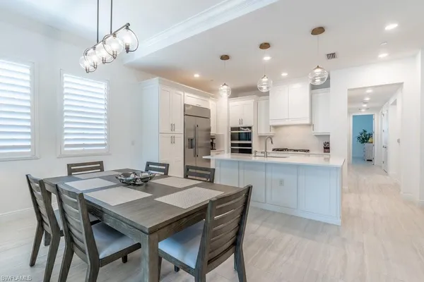 a kitchen with kitchen island a dining table chairs stainless steel appliances and cabinets