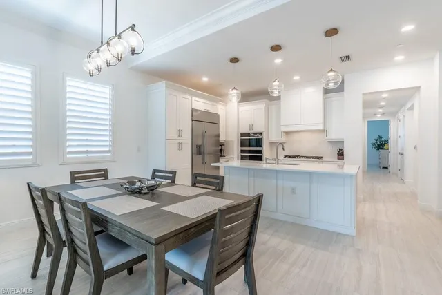 a kitchen with kitchen island a dining table chairs stainless steel appliances and cabinets