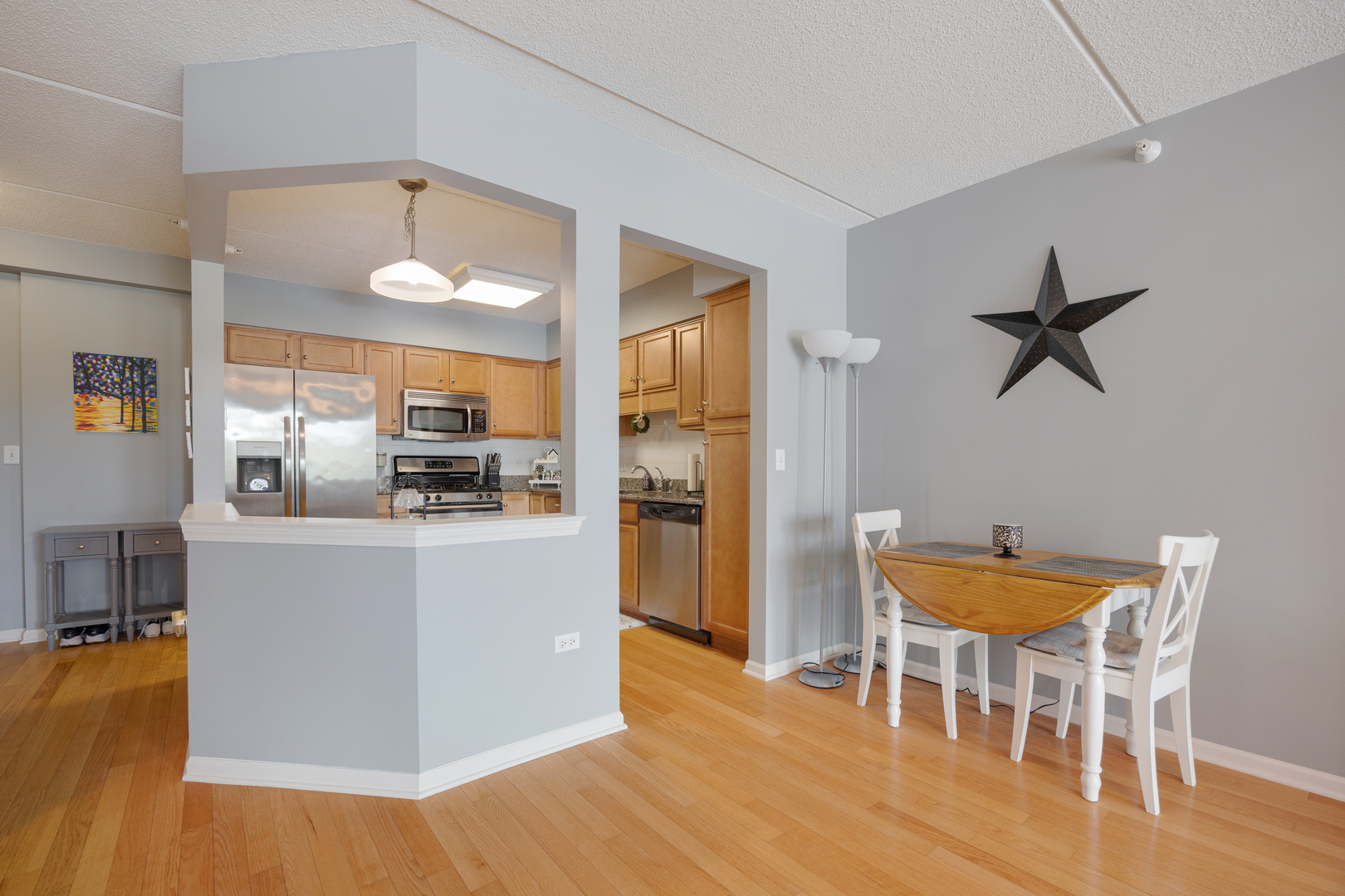 225 Main Street, Unit 216 Roselle, IL 60172 - Photo 8 of 20 a kitchen with stainless steel appliances kitchen island granite countertop a table chairs and a refrigerator