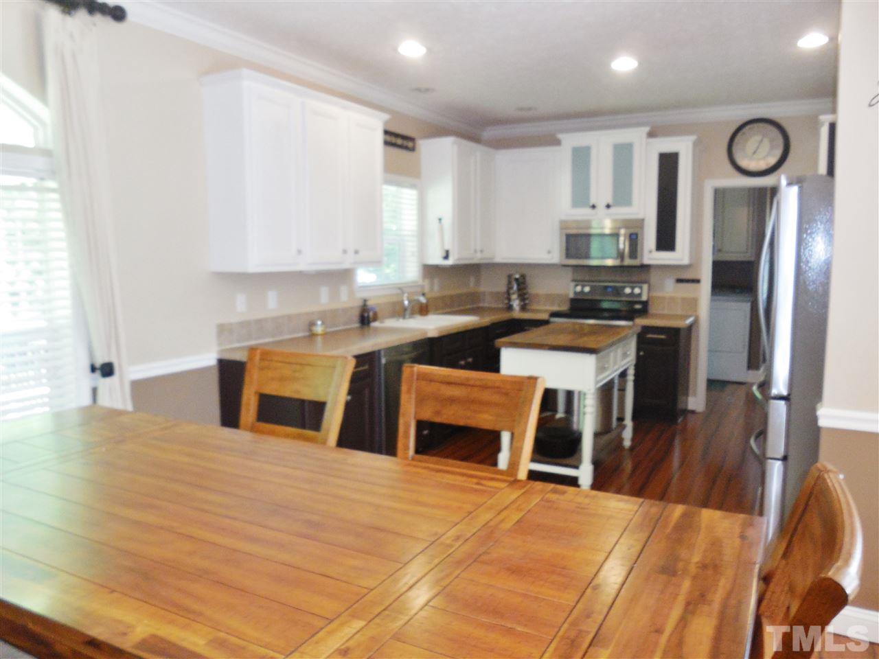 924 Whitt Town Road Roxboro, NC 27574 - Photo 6 of 17 a kitchen with stainless steel appliances granite countertop a stove top oven a sink dishwasher a dining table and chairs with wooden floor