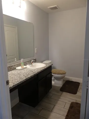 a bathroom with a granite countertop sink and a toilet