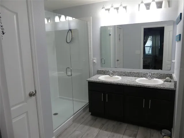 a bathroom with a sink vanity and shower