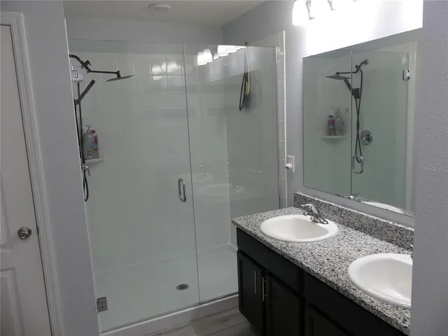 a bathroom with a granite countertop sink shower mirror and vanity