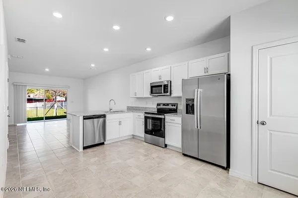 a large white kitchen with kitchen island a sink stainless steel appliances and cabinets