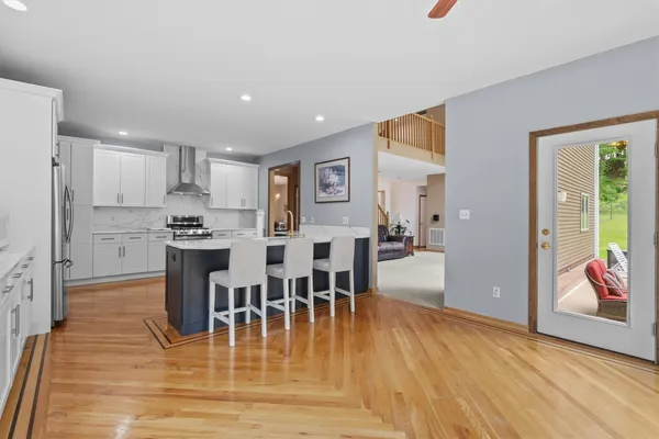 a kitchen with stainless steel appliances kitchen island granite countertop a dining table chairs and a refrigerator